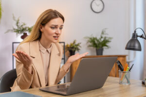 Middle-aged businesswoman at home office sees sales drop on laptop graph red arrow down frowns shrugs why feels stress.