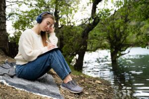 calm thoughtful woman writing in notebook keeping diary relaxing study listening to a podcast about setting goals